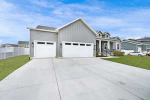 View of front of property with a porch, a garage, and a front lawn