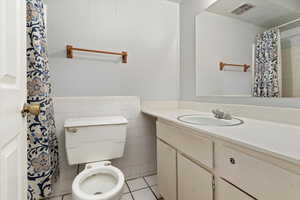 Bathroom with toilet, vanity, tile patterned floors, and tile walls