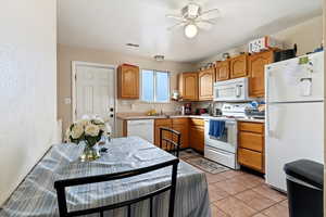 Kitchen featuring sink, white appliances, ceiling fan, and light tile patterned flooring