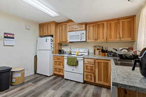 Kitchen featuring light hardwood / wood-style floors, white appliances, and sink