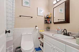 Bathroom with vanity, toilet, and tile walls