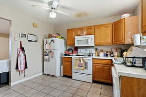 Kitchen featuring ceiling fan, light tile patterned floors, and white appliances