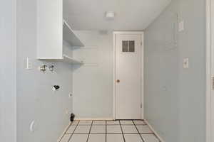 Washroom with hookup for an electric dryer, light tile patterned floors, and hookup for a washing machine