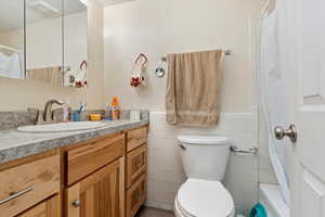 Bathroom with vanity, toilet, and tile walls