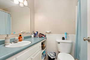 Bathroom featuring vanity, toilet, and tile walls