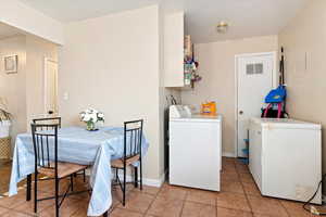 Laundry area with washer and dryer and light tile patterned floors