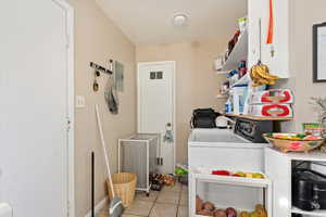 Laundry room with washing machine and dryer and light tile patterned floors