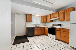 Kitchen with light tile patterned flooring, white appliances, and sink