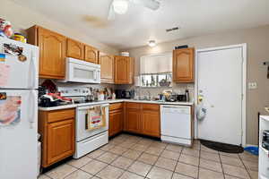 Kitchen with ceiling fan, sink, light tile patterned floors, and white appliances