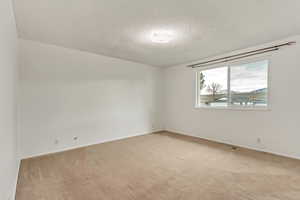 Carpeted empty room featuring a textured ceiling