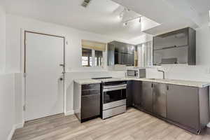 Kitchen featuring light stone countertops, sink, light wood-type flooring, and stainless steel appliances