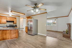 Kitchen featuring ceiling fan, stainless steel appliances, a textured ceiling, and light hardwood / wood-style floors