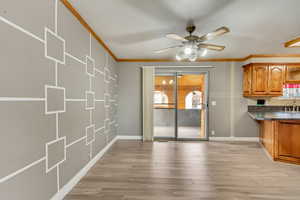 Unfurnished dining area featuring light wood-type flooring, ceiling fan, crown molding, and sink