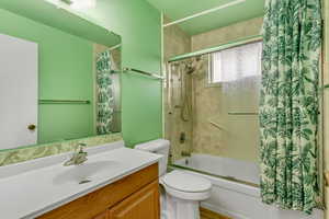 Full bathroom with vanity, tiled shower / bath combo, and toilet