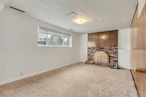 Interior space featuring carpet, a brick fireplace, and wood walls