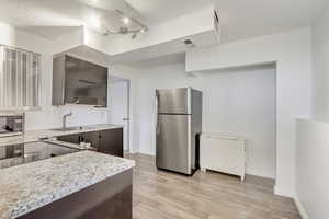 Kitchen with dark brown cabinetry, sink, appliances with stainless steel finishes, and light hardwood / wood-style flooring