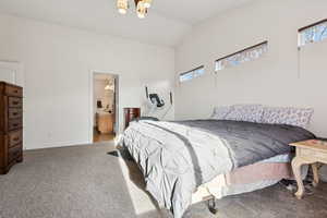 Bedroom featuring carpet flooring, connected bathroom, and vaulted ceiling