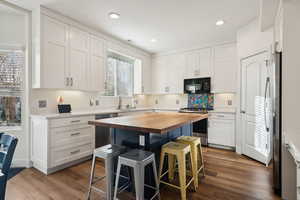 Kitchen with wood counters, a kitchen bar, stainless steel appliances, and white cabinets