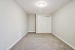 Unfurnished bedroom featuring light carpet, a closet, and a textured ceiling