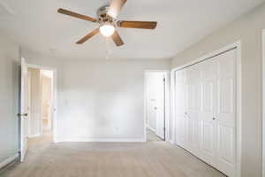 Unfurnished bedroom featuring light carpet, a closet, and ceiling fan