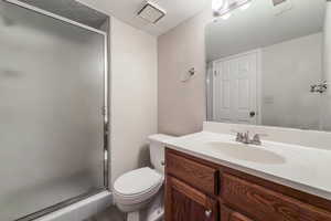 Bathroom featuring tile patterned floors, a textured ceiling, toilet, vanity, and a shower with shower door