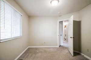 Carpeted spare room with a textured ceiling