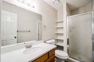 Bathroom with a shower with door, vanity, and toilet