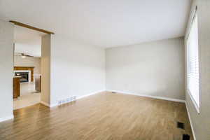 Unfurnished room featuring a tile fireplace, hardwood / wood-style flooring, and ceiling fan