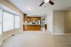 Kitchen with kitchen peninsula, light wood-type flooring, stainless steel appliances, and a wealth of natural light