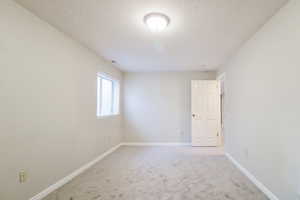 Carpeted spare room featuring a textured ceiling