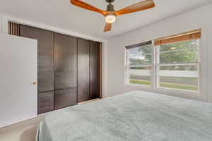 Carpeted bedroom featuring ceiling fan and a closet