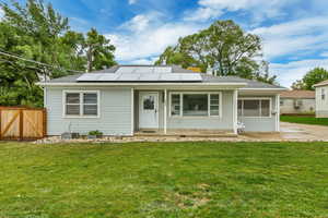 View of front of home with solar panels and a front yard