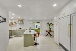 Kitchen featuring a breakfast bar area, white cabinetry, extractor fan, and light hardwood / wood-style floors