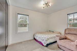 Bedroom featuring a notable chandelier, light colored carpet, and multiple windows