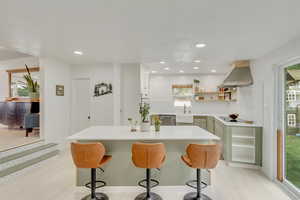 Kitchen featuring sink, white stovetop, stainless steel dishwasher, island exhaust hood, and light hardwood / wood-style floors