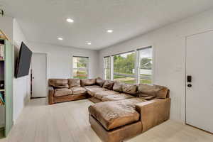 Living room with light hardwood / wood-style flooring and a textured ceiling