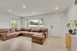 Living room with a textured ceiling and light hardwood / wood-style flooring