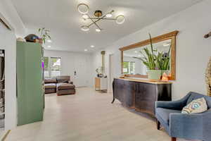 Interior space with plenty of natural light, a chandelier, a textured ceiling, and light hardwood / wood-style flooring