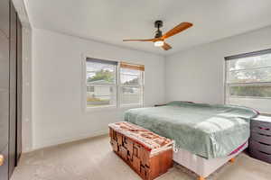 Carpeted bedroom with ceiling fan and a closet