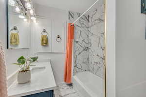 Bathroom featuring vanity and shower / bathtub combination with curtain