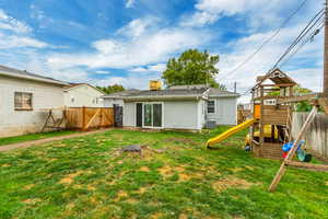 Back of property with a lawn, a playground, and central AC