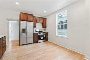 Kitchen featuring tasteful backsplash, light wood-type flooring, and appliances with stainless steel finishes