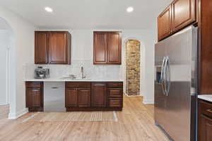 Kitchen featuring stainless steel appliances, light hardwood / wood-style flooring, tasteful backsplash, and sink