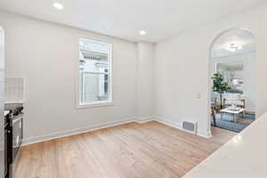 Kitchen with light hardwood / wood-style floors, light stone countertops, and stainless steel gas range