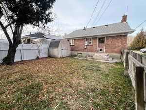 Rear view of house with a storage shed and a yard