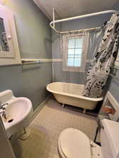 Full bathroom with shower / bath combo with shower curtain, sink, tile walls, and toilet