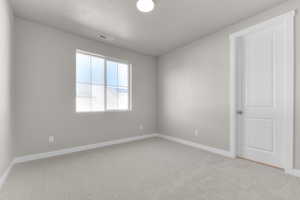 Empty room featuring light colored carpet and a textured ceiling