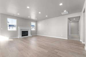 Unfurnished living room featuring light hardwood / wood-style flooring and a textured ceiling