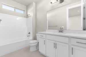 Full bathroom with vanity, tile patterned floors, washtub / shower combination, and toilet