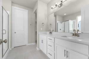 Bathroom featuring a shower with door, vanity, and tile patterned flooring